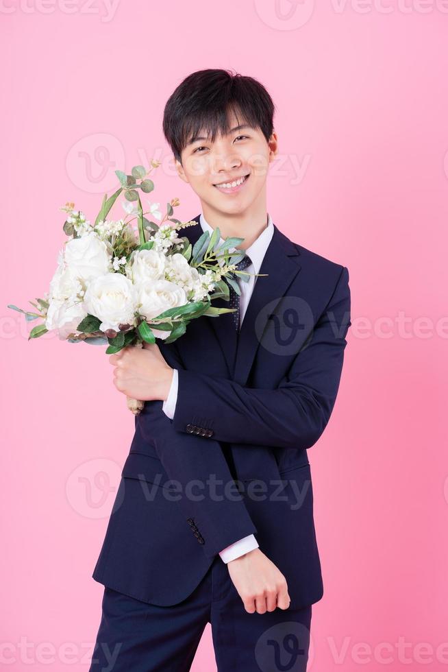 Young Asian groom posing on pink background photo