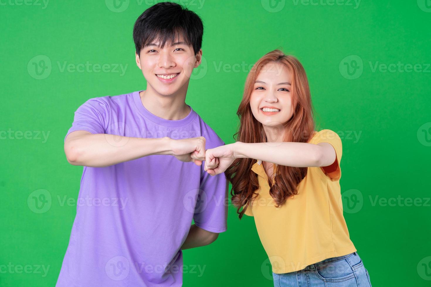 Young Asian couple posing on green background photo