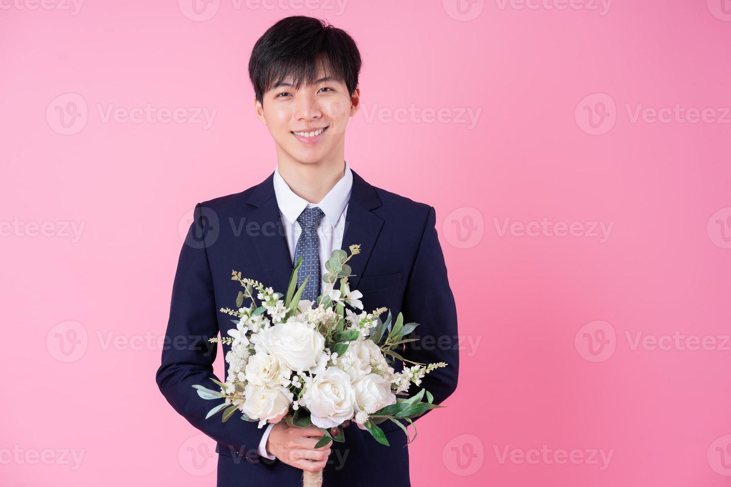 joven novio asiático posando sobre fondo rosa foto