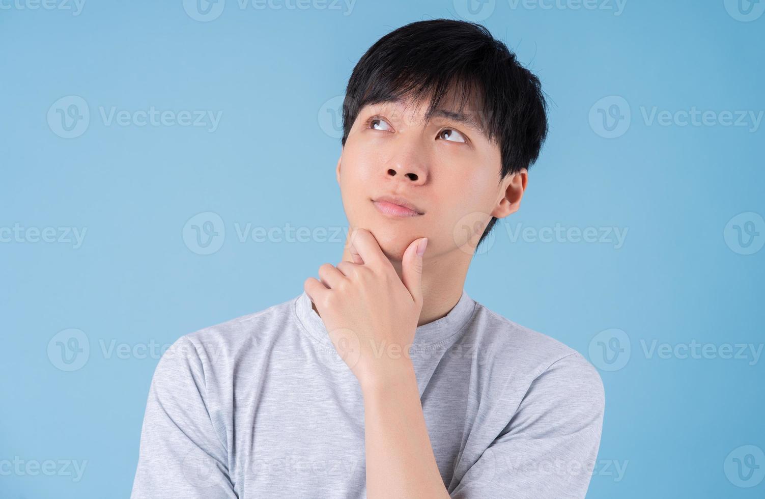 Young Asian man posing on blue background photo