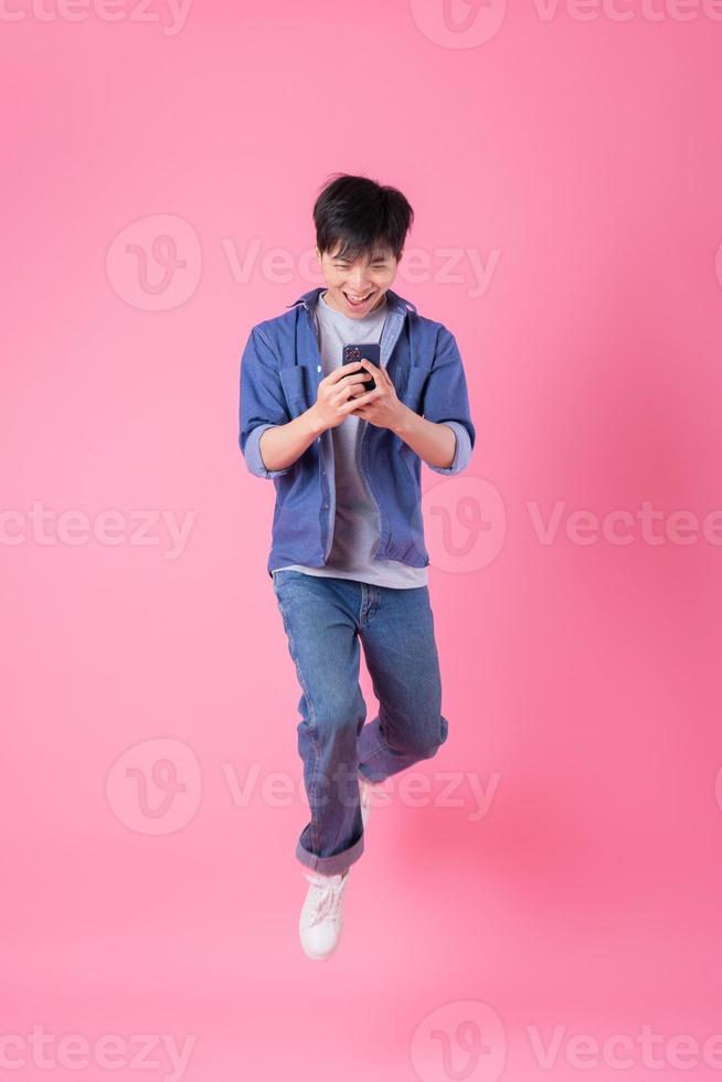 Young Asian man jumping on blue background photo