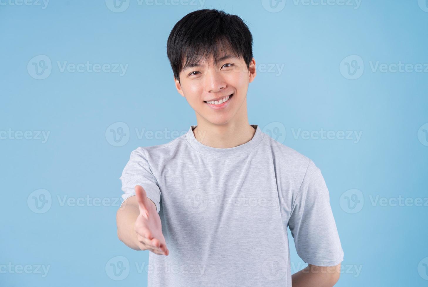 Young Asian man posing on blue background photo