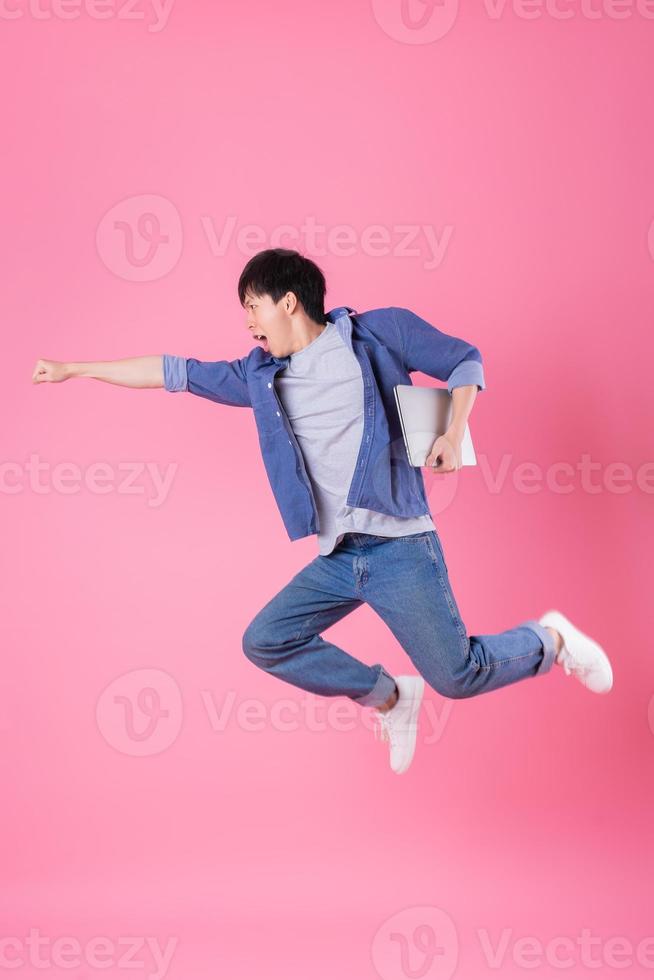 Young Asian man jumping on blue background photo