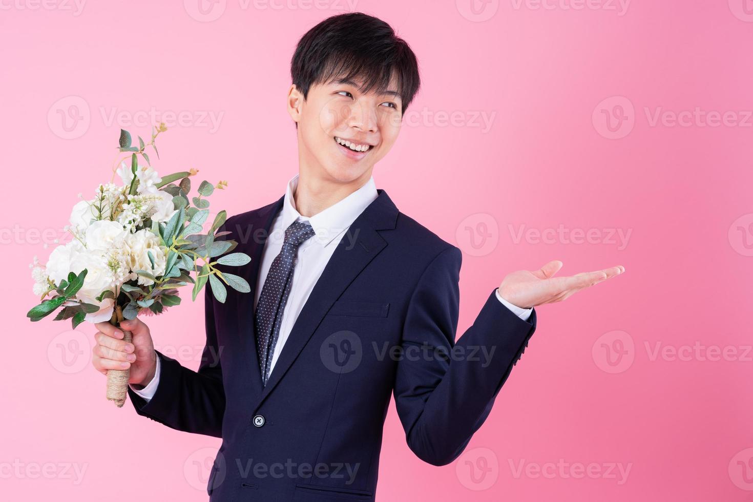 joven novio asiático posando sobre fondo rosa foto