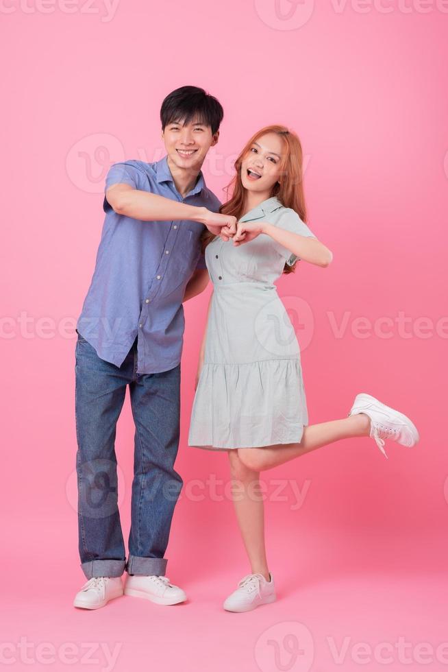 Young Asian couple posing on pink background photo