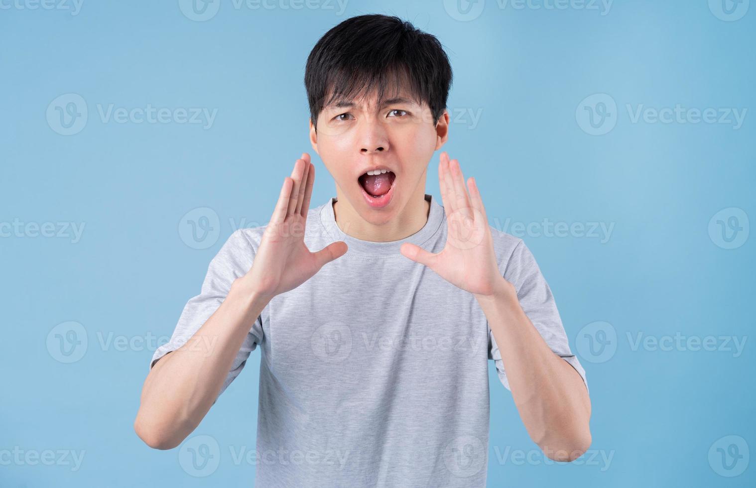 Young Asian man posing on blue background photo