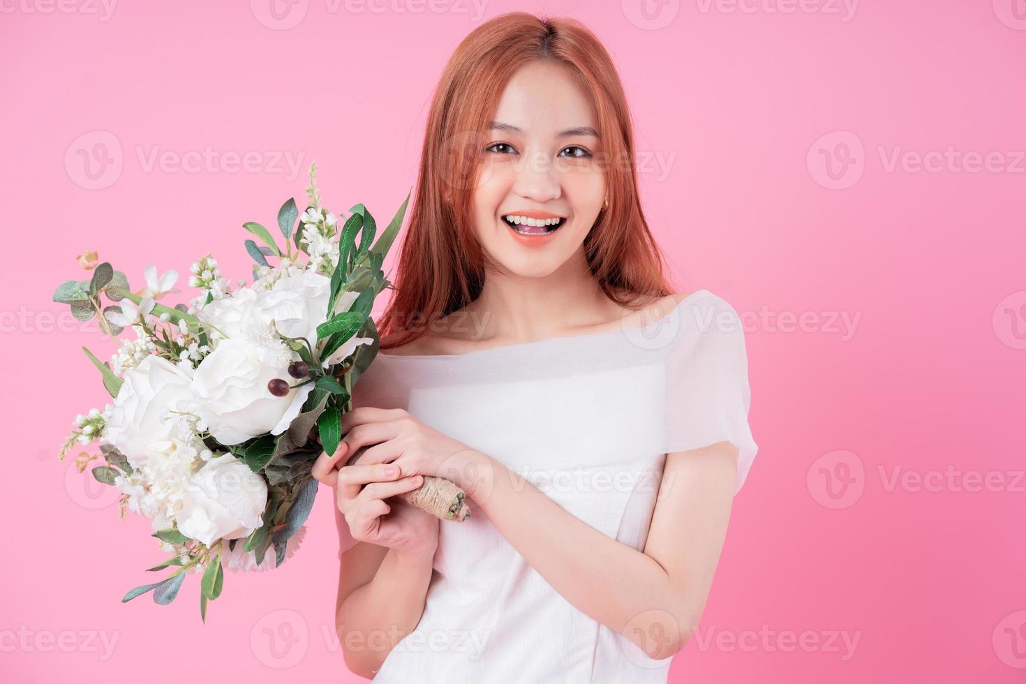 joven novia asiática posando sobre fondo rosa foto