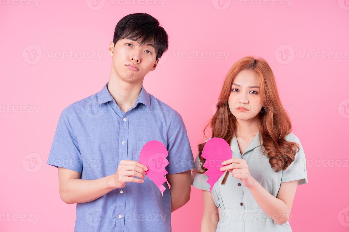 Young Asian couple posing on pink background photo