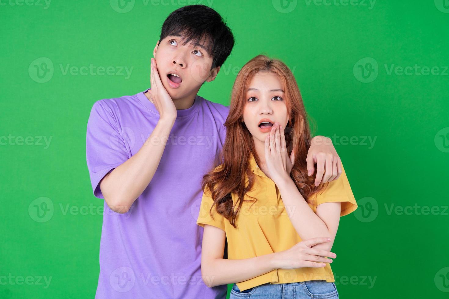 Young Asian couple posing on green background photo