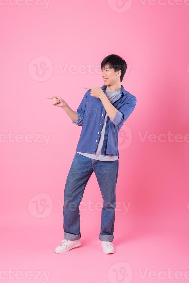 Young Asian man posing on pink background photo