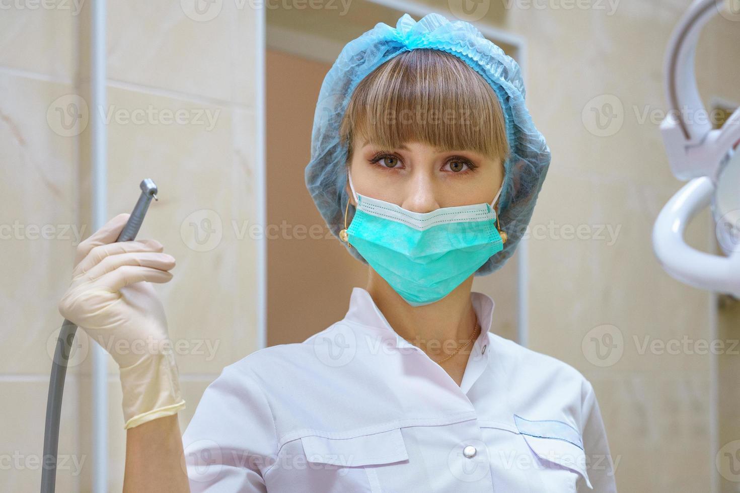 a female dentist holds a boron machine in her hand photo