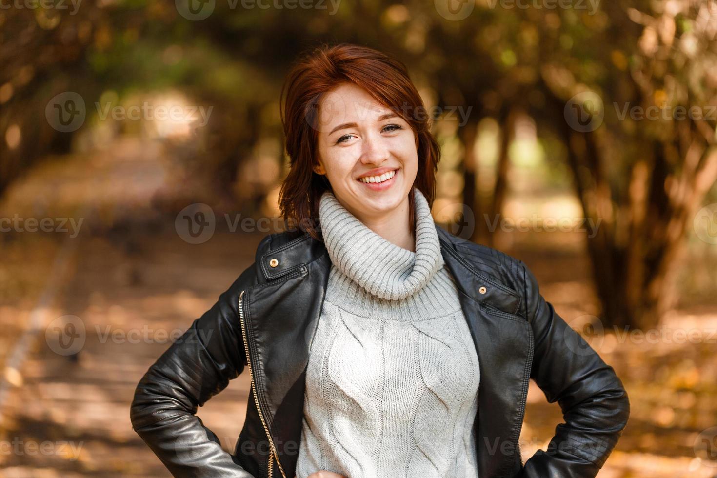 Happy young woman relaxing in autumn nature. In gray sweater and  leather photo