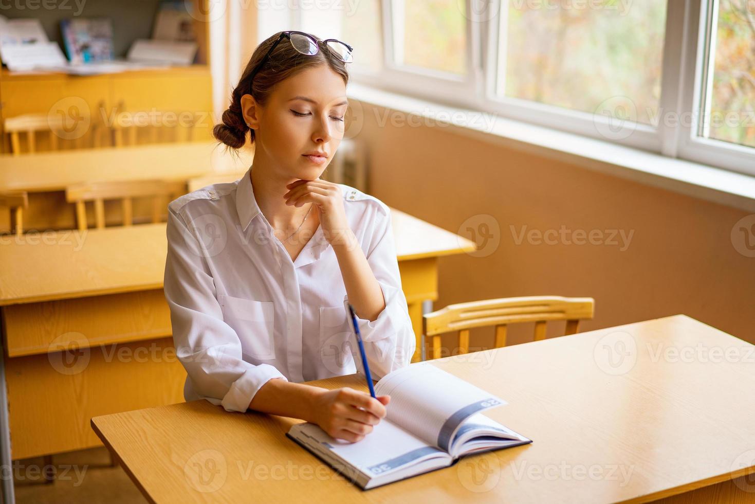 cute student sitting with a notebook at the Desk by the window, thoughtful view photo
