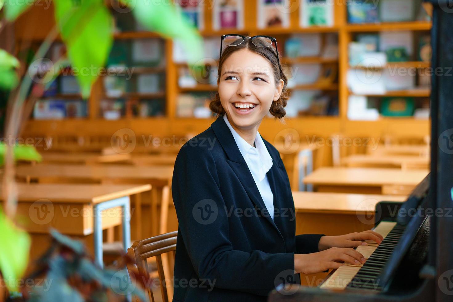 young beautiful woman playing the piano in class photo