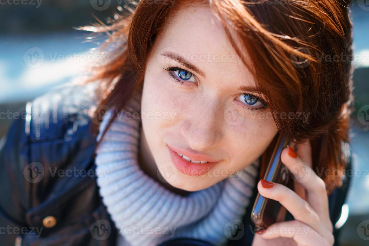 Redhead girl talking on the phone. Close-up portrait, beautiful eyes photo