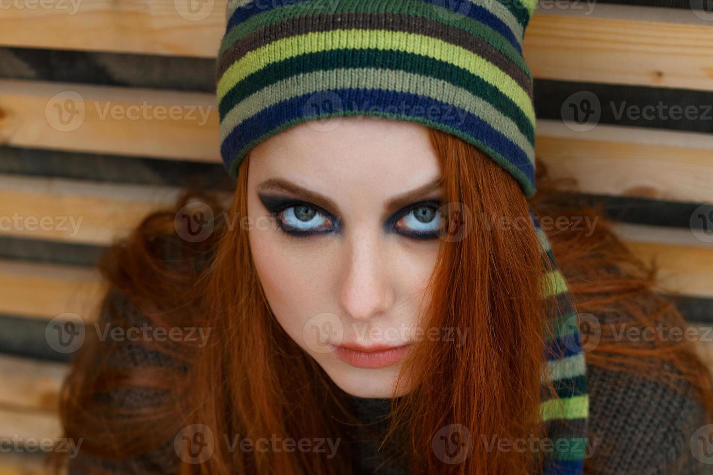 Portrait of a woman with a bright make up in a funny hat looking at the camera photo