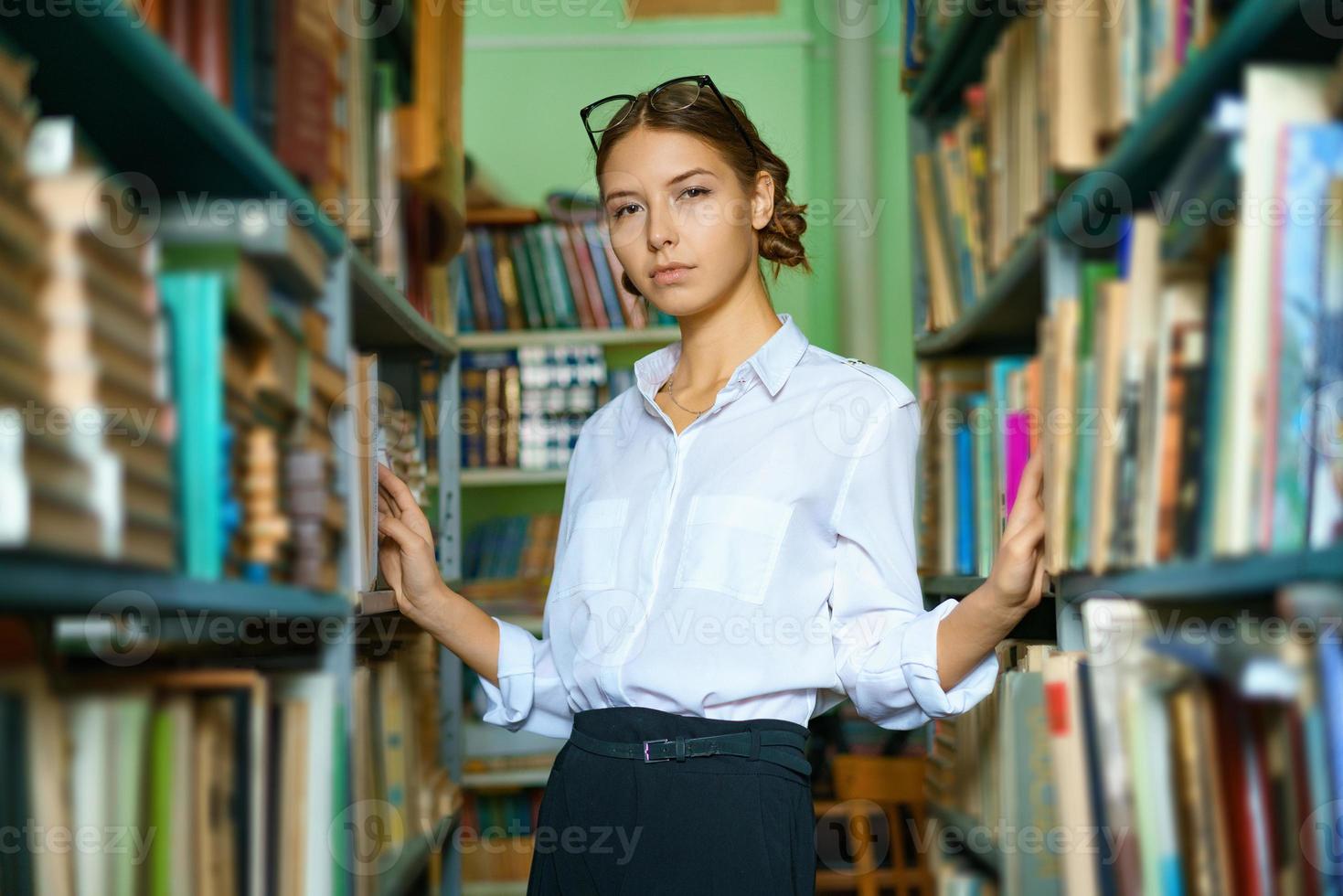 una buena mujer con una camisa blanca en la biblioteca está sonriendo foto