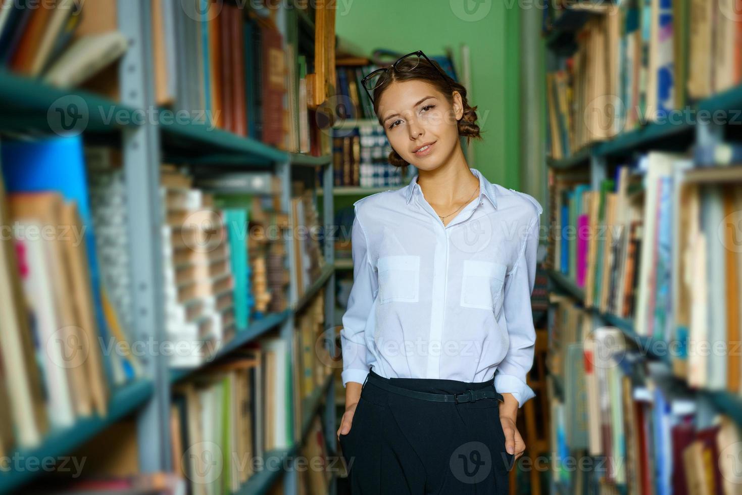 A nice woman in a white shirt in the library is smiling photo