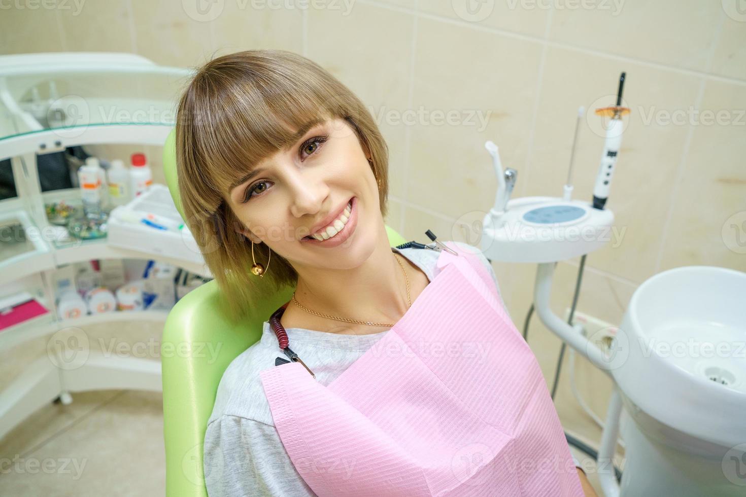 mujer feliz sentada en el consultorio del dentista, dientes sanos foto