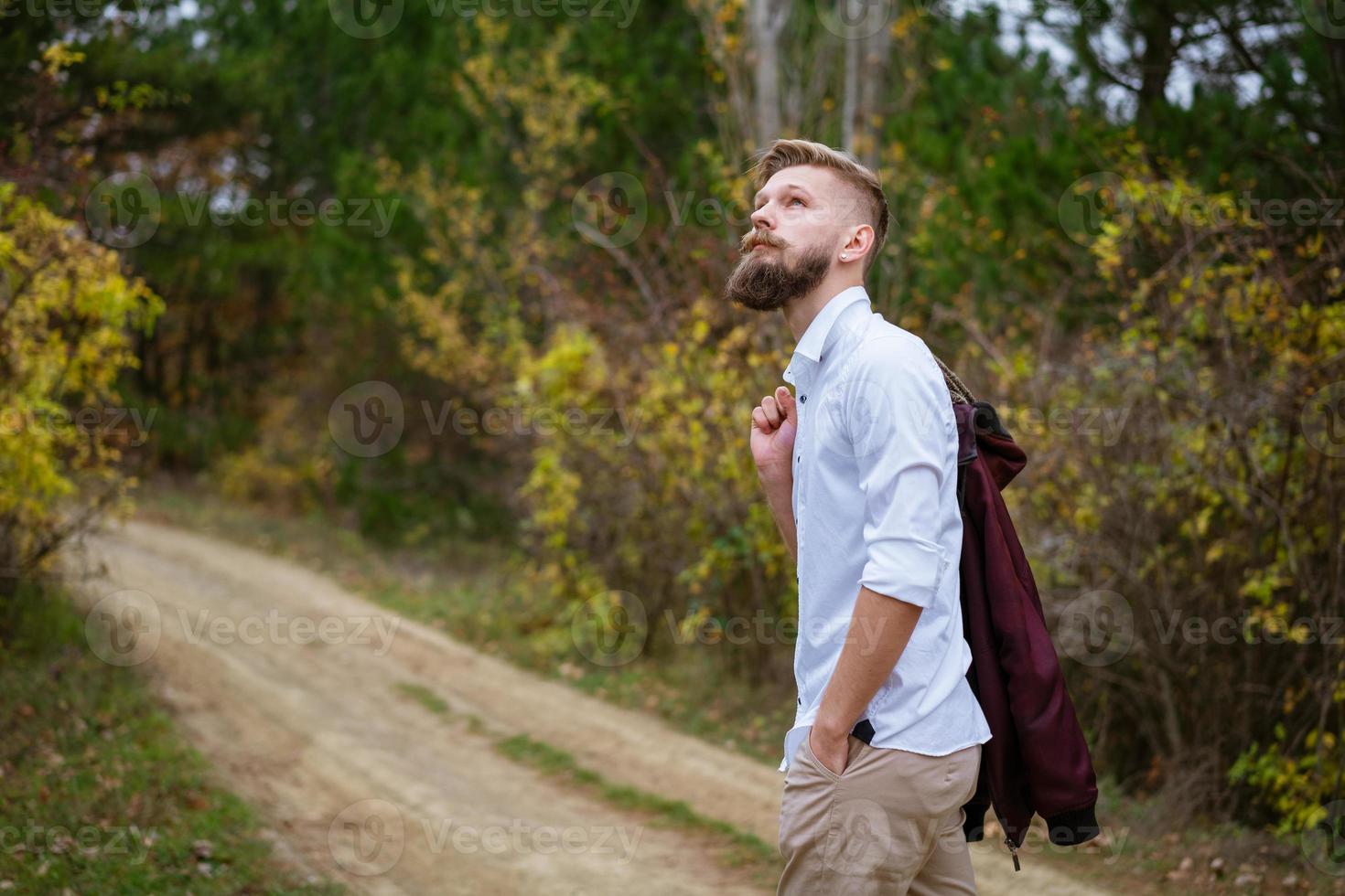 retrato de un joven barbudo caminando por la carretera en el parque en otoño. foto