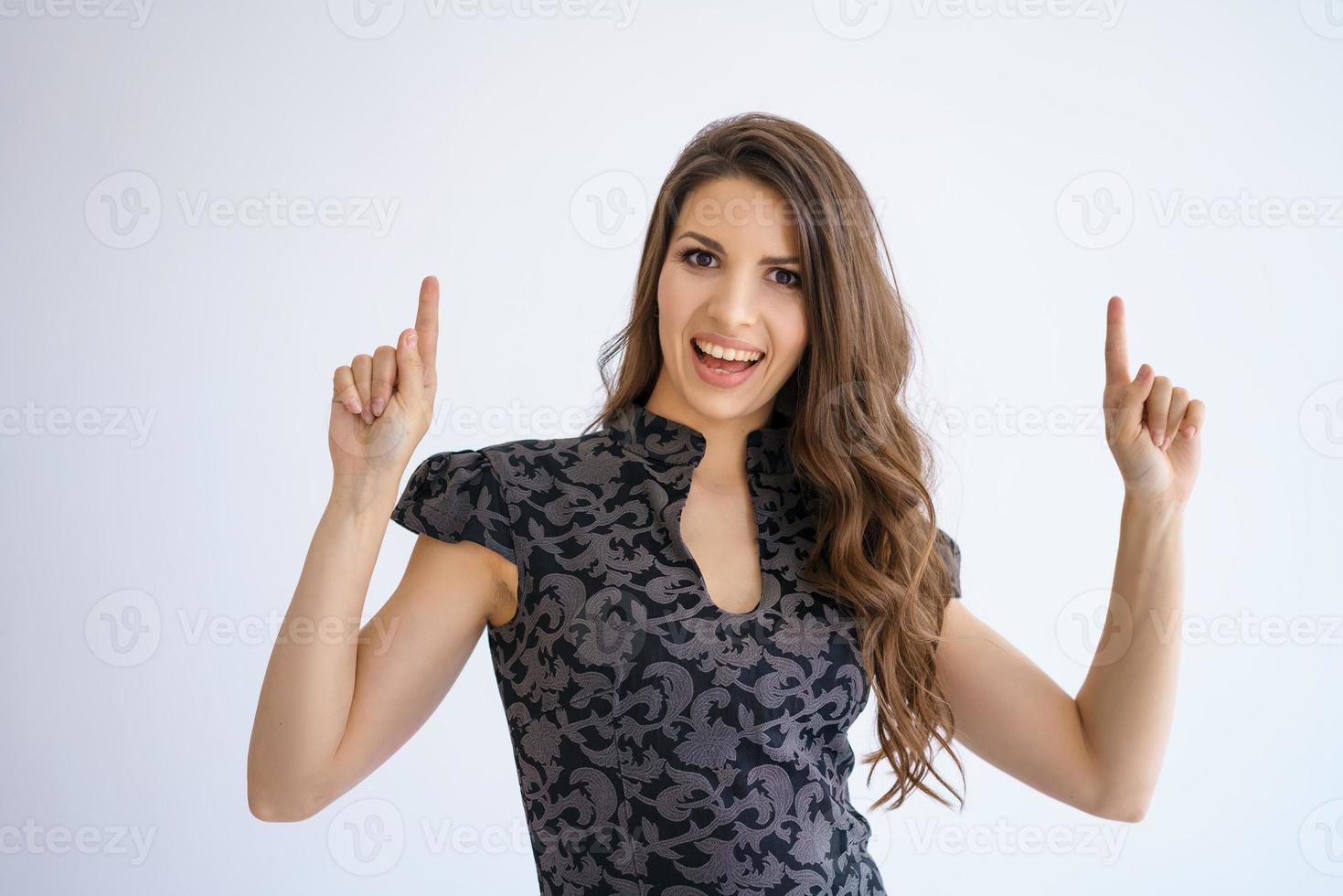 woman in a dress poses on a white background, raises her fingers up photo