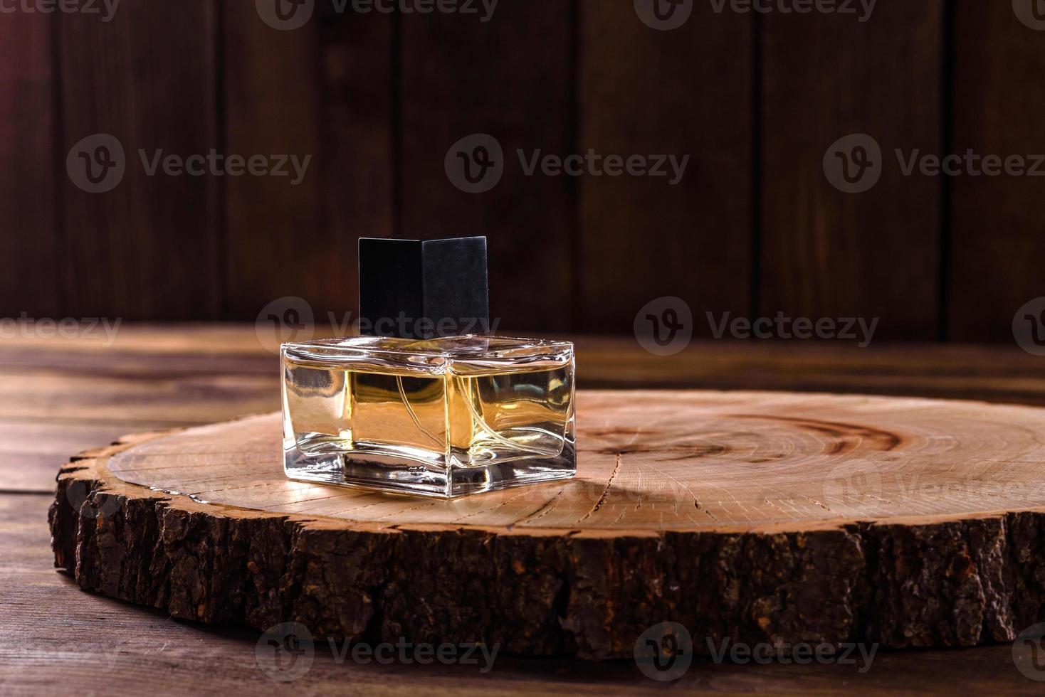 Glass perfume bottle with rosemary sprig on wooden podium photo