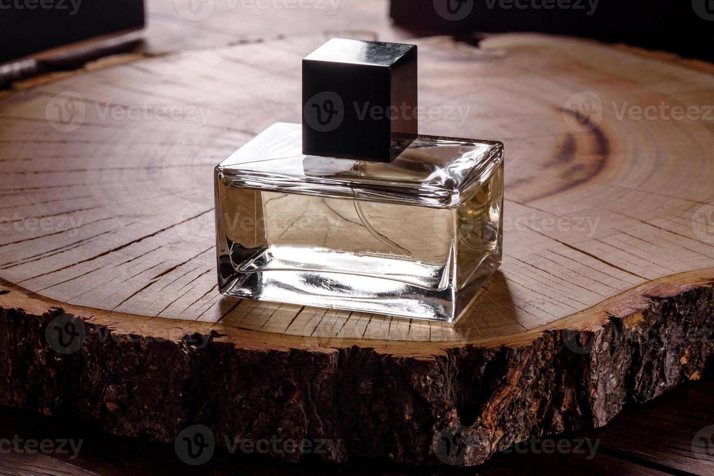 Glass perfume bottle with rosemary sprig on wooden podium photo