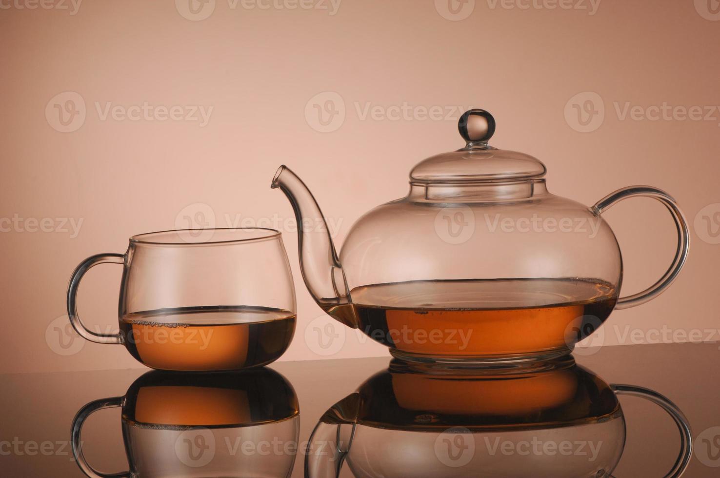 Transparent glass teapot and cup with tea photo