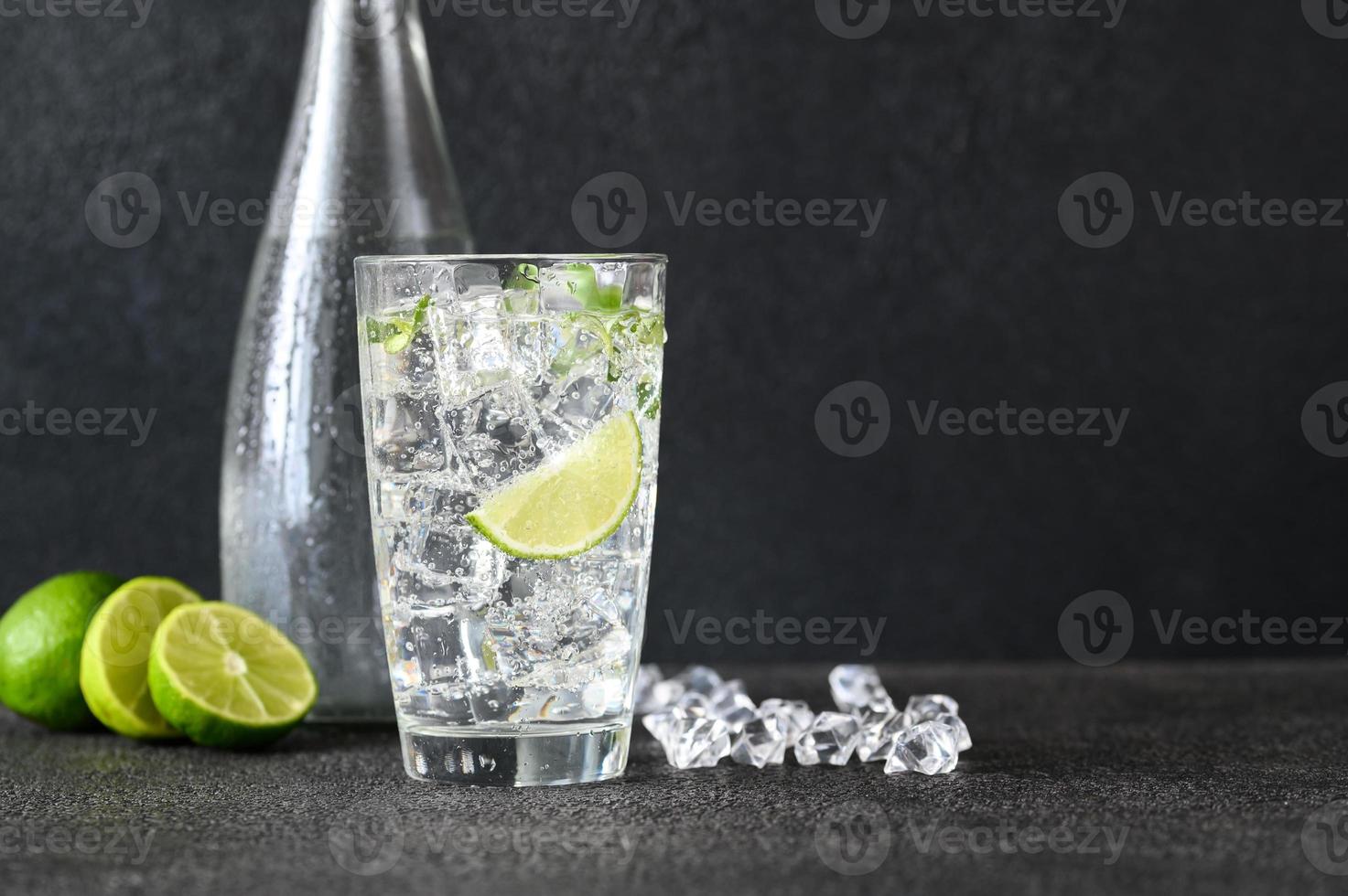 Glass of sparkling water with ice cubes and slice of lime photo