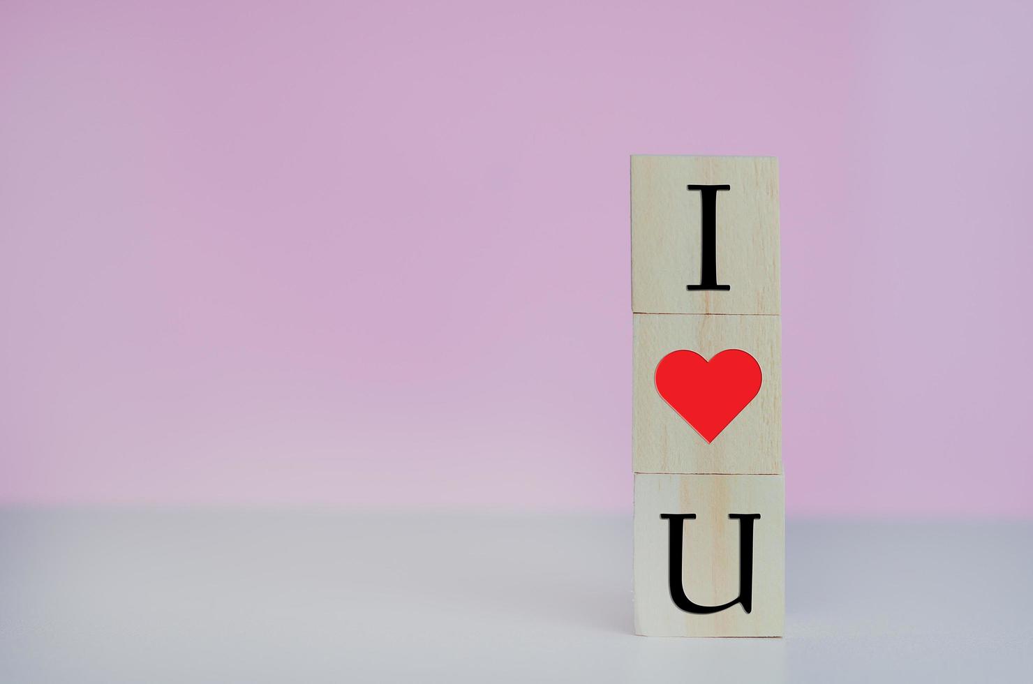 Wooden cubes with i love u symbol heart on the pink background and copy space. photo