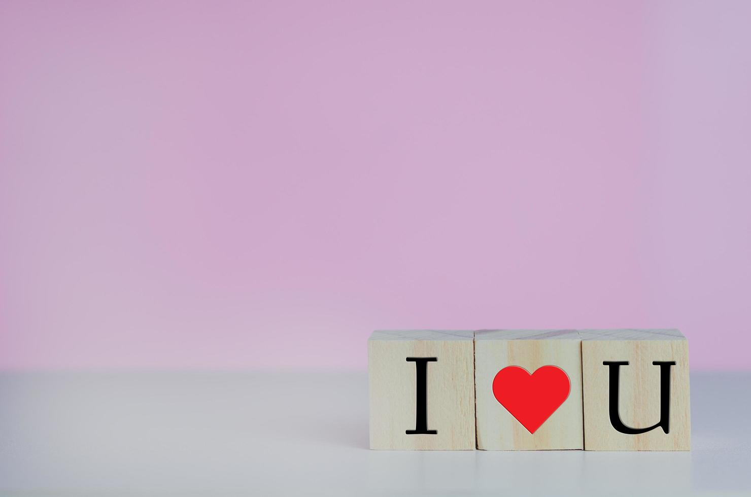 cubos de madera con te amo corazón de símbolo en el fondo rosa y espacio de copia. foto