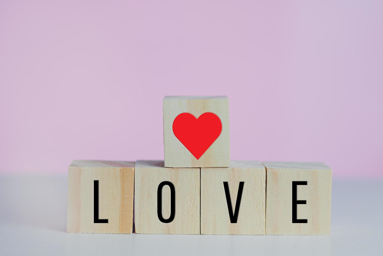 Wooden cubes with love  symbol heart on the pink background and copy space. photo