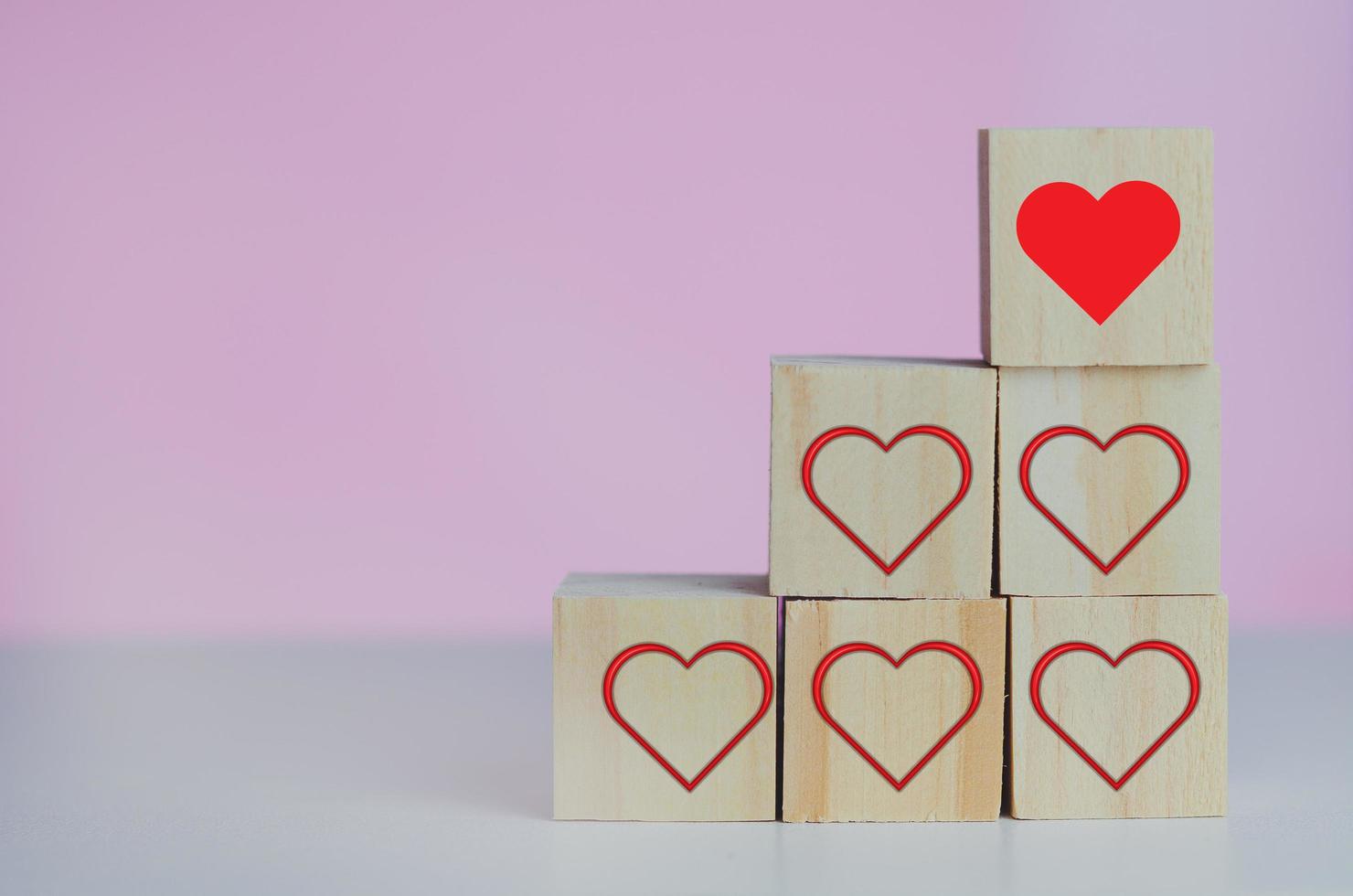 Wooden cubes with love  symbol heart red on the pink background and copy space. photo