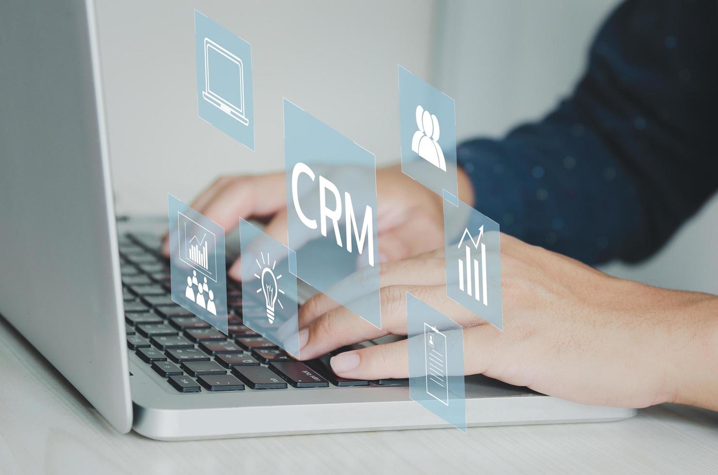 escribiendo a mano en concepto de portátil. iconos crm negocio de gestión de relaciones con clientes en pantalla virtual. foto