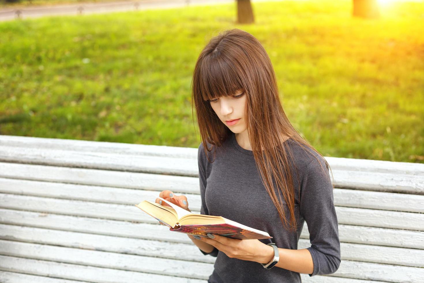 a young woman in the Park reading a book on a Sunny summer day photo