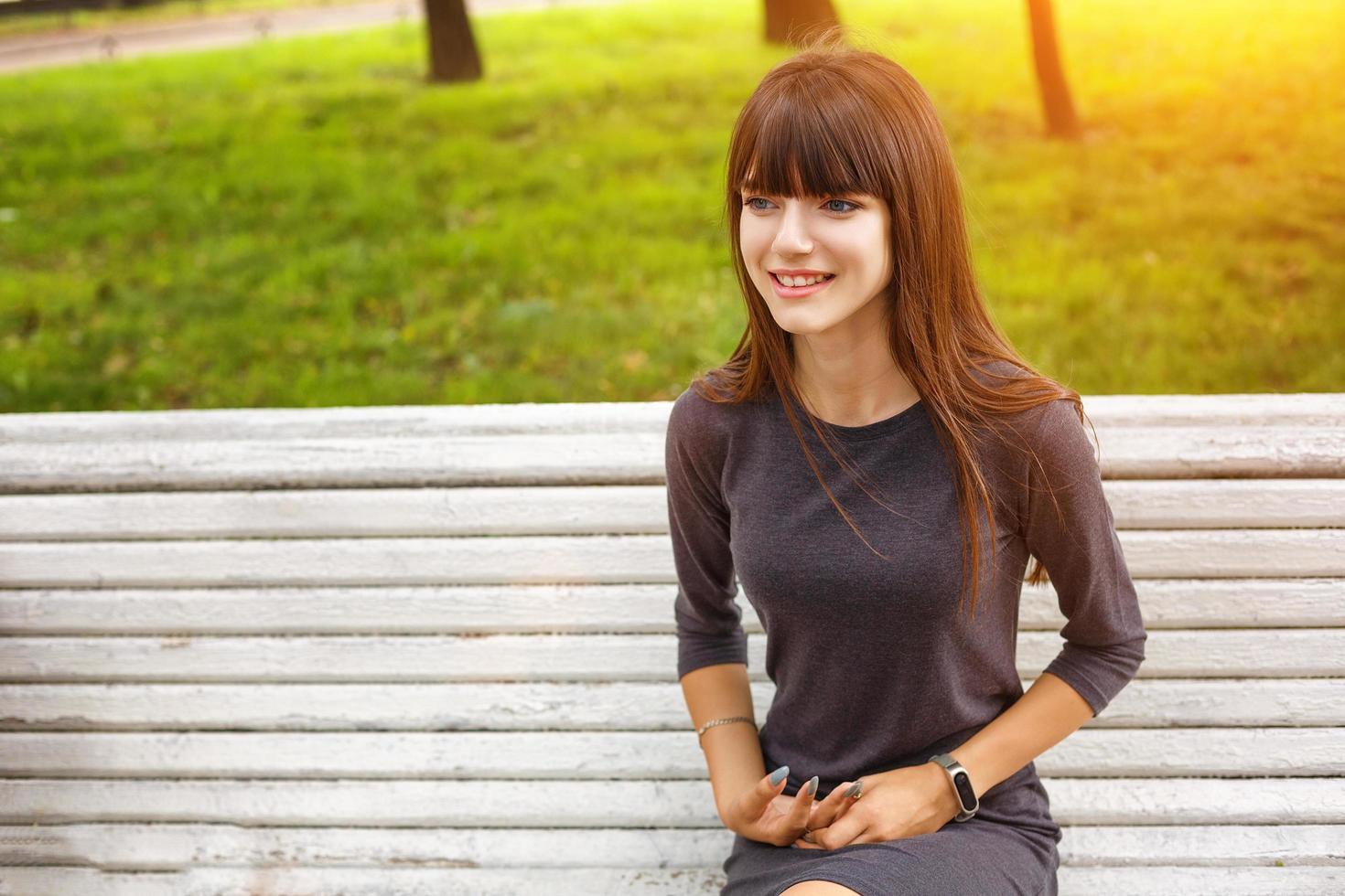 young woman in the Park sitting on a bench happy smile, the concept of relaxation and happy mood photo