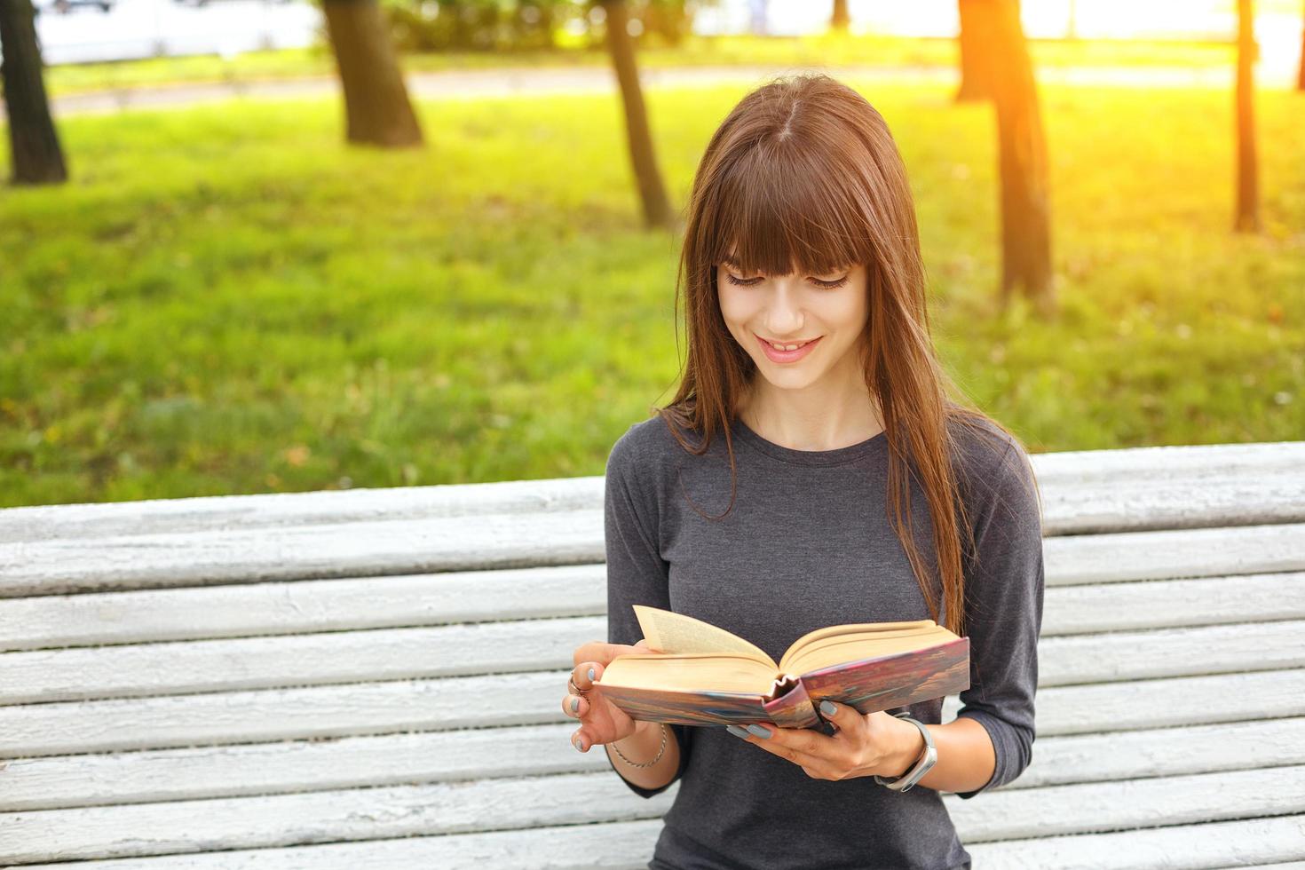 a young woman in the Park reading a book on a Sunny summer day photo