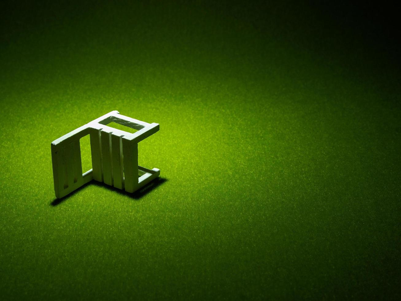 White wooden chair on artificial grass. Light shining down from above in the dark tone low key photo