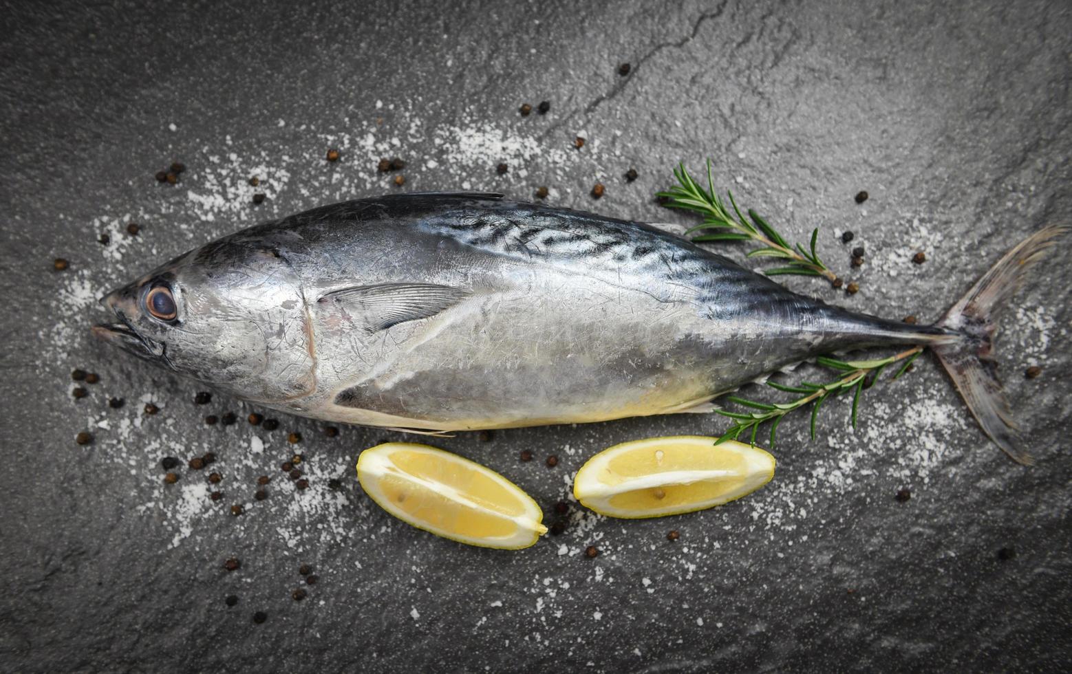Fresh fish with herbs spices rosemary and lemon - Raw fish seafood on black plate background top view , Longtail tuna , Eastern little tuna fish photo