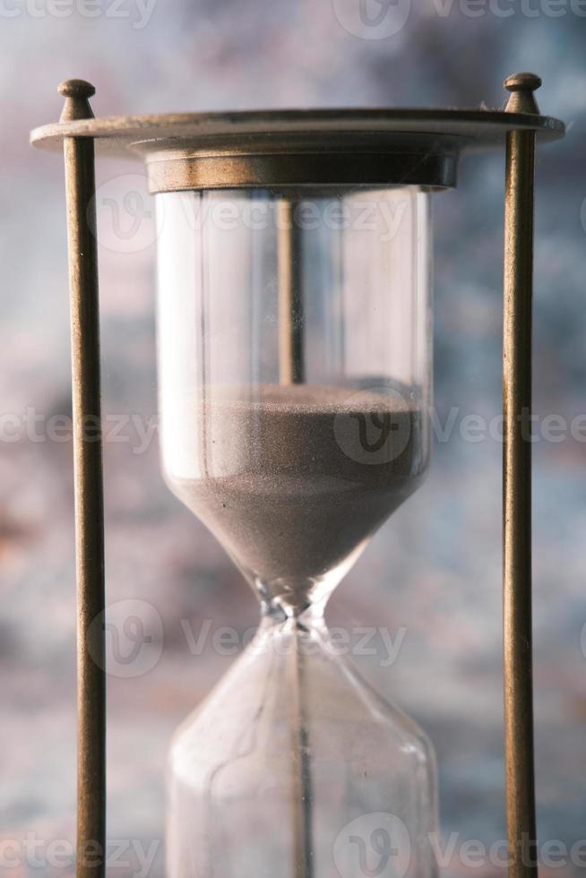 hourglass on table, sand flowing through the bulb of sandglass photo