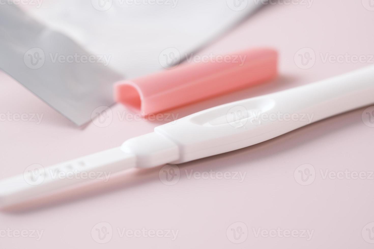 Pregnancy test kit and plastic packet on light color background photo