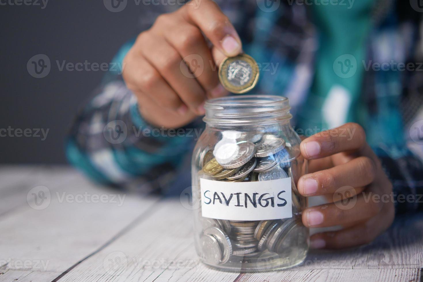 child boy hand hold a saving coins jar photo