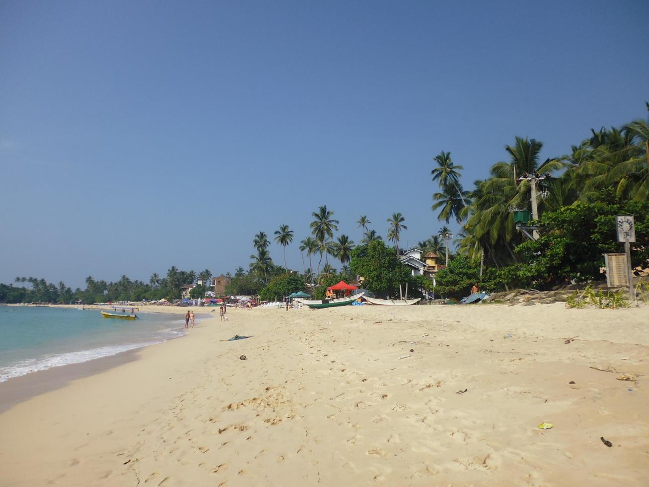 Wide sandy beach with boats in the distance photo