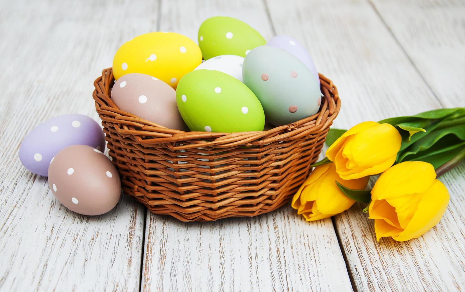 Basket with easter eggs and tulips photo
