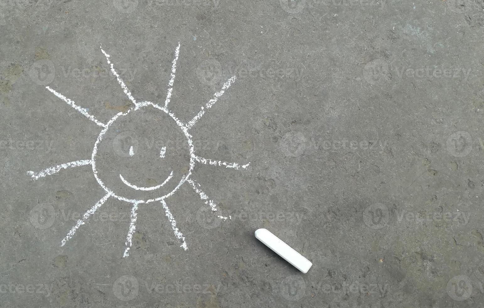 sun with a smile is drawn in chalk on the asphalt. banner with place for your text, copy space. children creativity, summer joy emotion photo