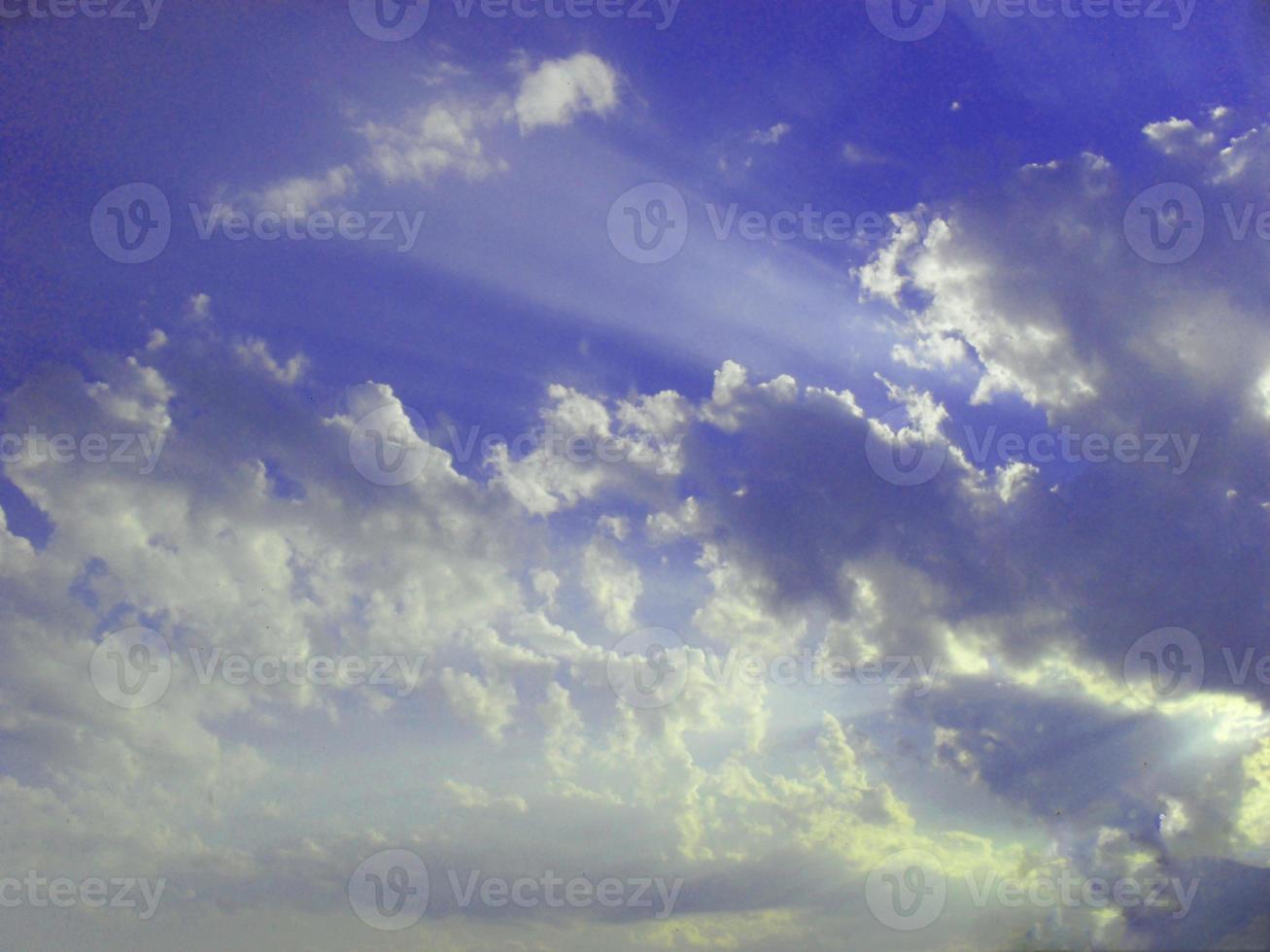 rays of the sun through white clouds in a blue sky natural background photo