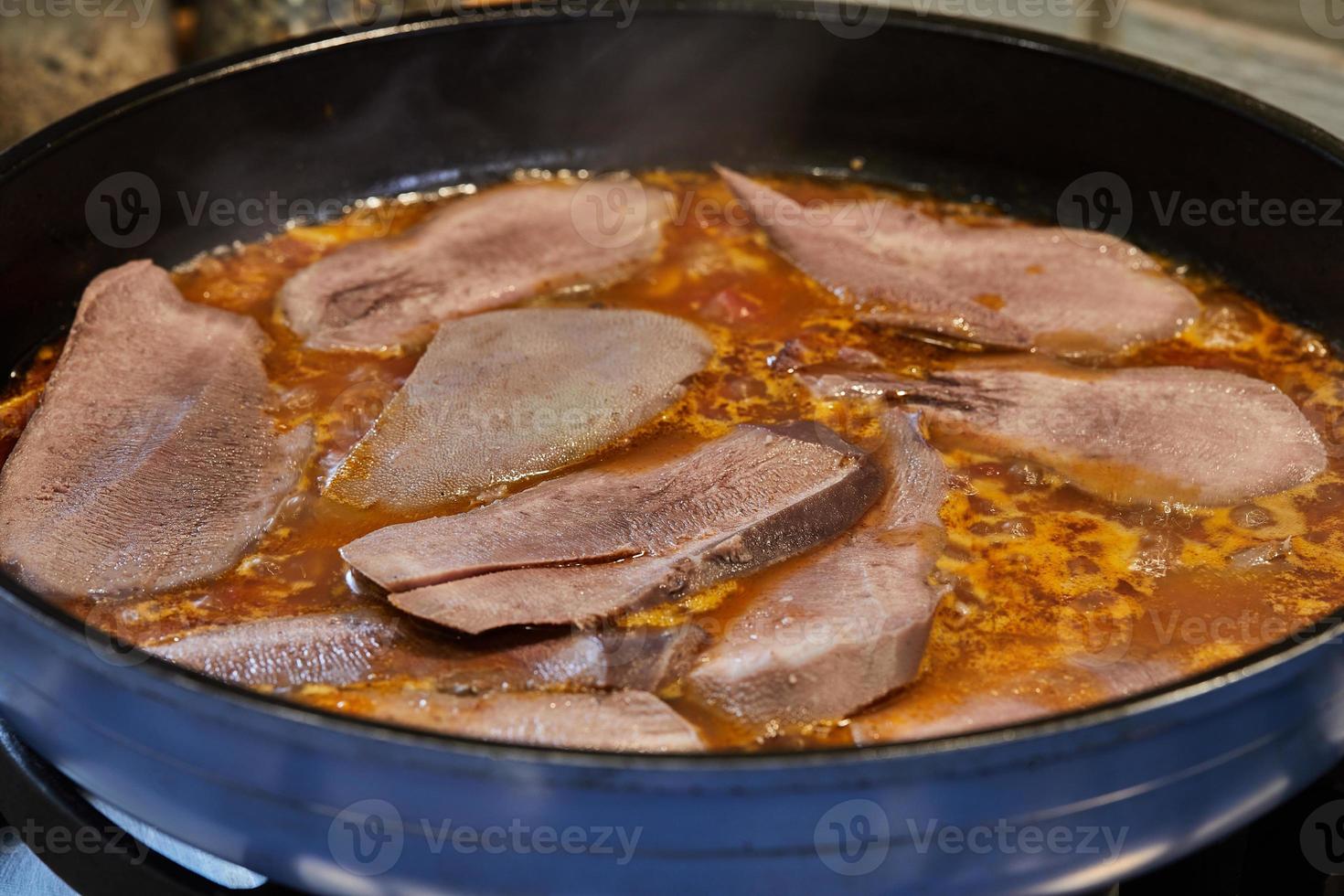 Veal tongue with tomato sauce, mushrooms and capers is fried in frying