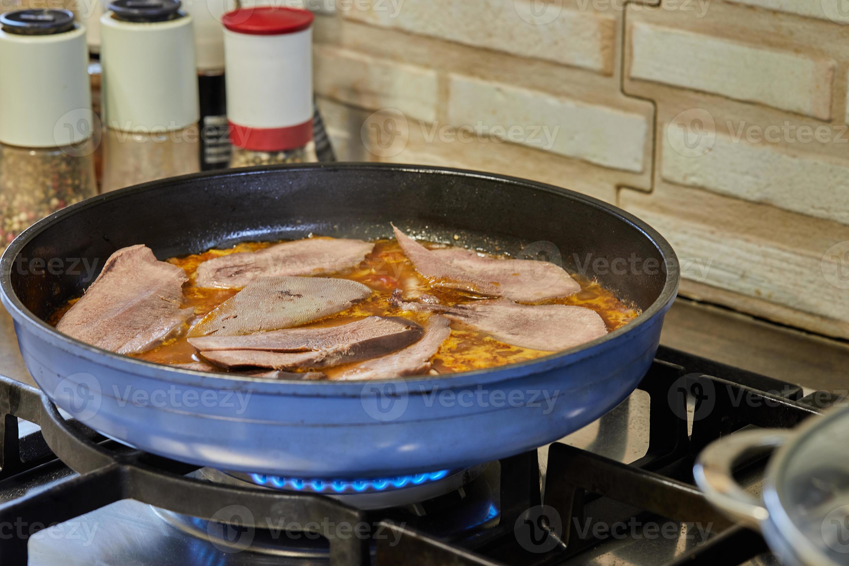 Veal tongue with tomato sauce, mushrooms and capers is fried in frying