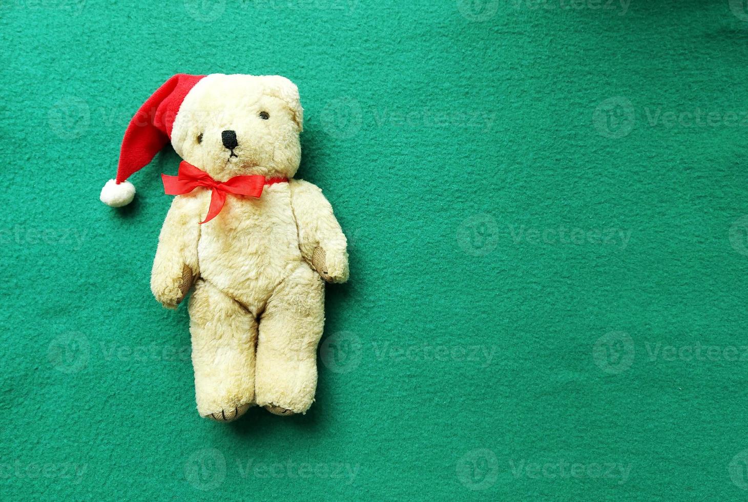 toy polar bear in red santa claus hat with a bow on a green background. christmas banner. copy space, place for text, animal, flyer, invitation, flatlay photo