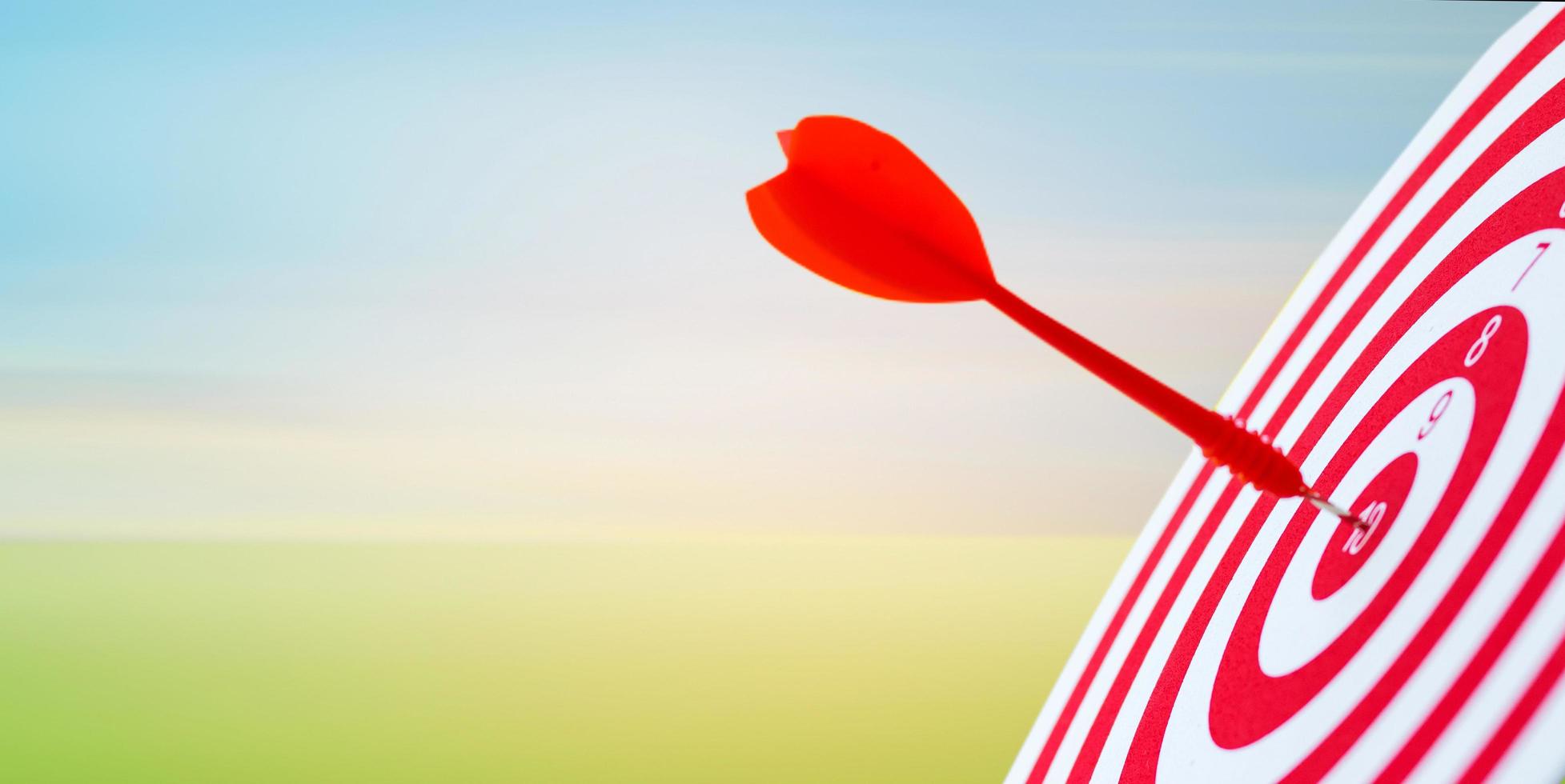 Close-up red dart arrow hitting in target center of dartboard sky background  Business goal or success goal marketing Strategy and business competition concept photo